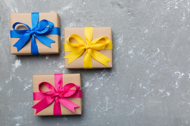 Holiday gift box wrapped in craft paper with colored bow on table background Top view flat lay copy space