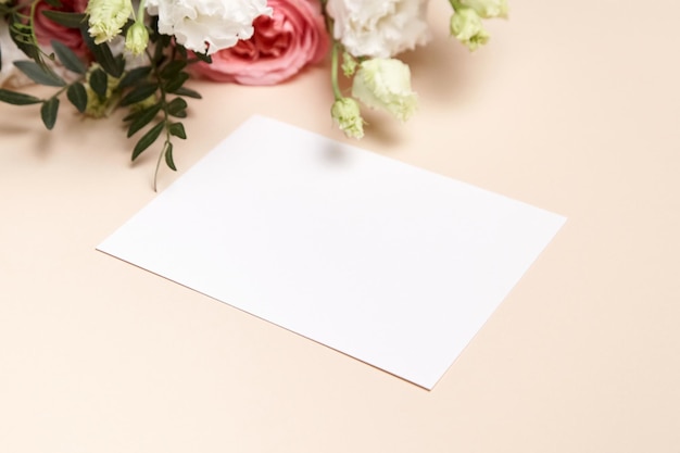 Holiday greeting card mockup with bouquet of flowers on light beige background White wedding invitation card mockup and floral decor