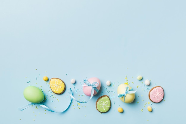 Holiday preparation Multi colors Easter eggs with cookies on colored background Pastel color Easter eggs holiday concept with copy space