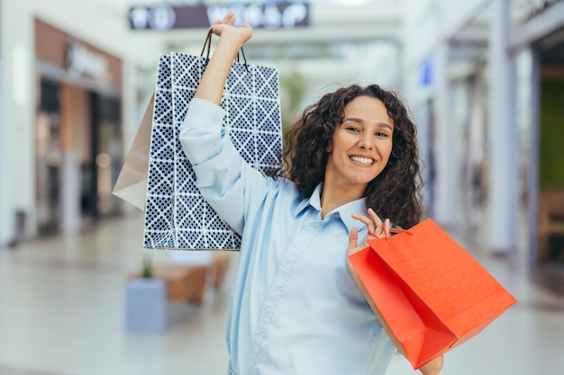 Holiday sale black friday happy young hispanic woman shopping in a supermarket she holds colored