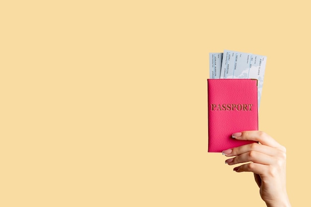 Holiday tourism Travel agency Female hand holding international passport in pink cover first class flight ticket isolated on pastel peach copy space Advertisement background Vacation trip