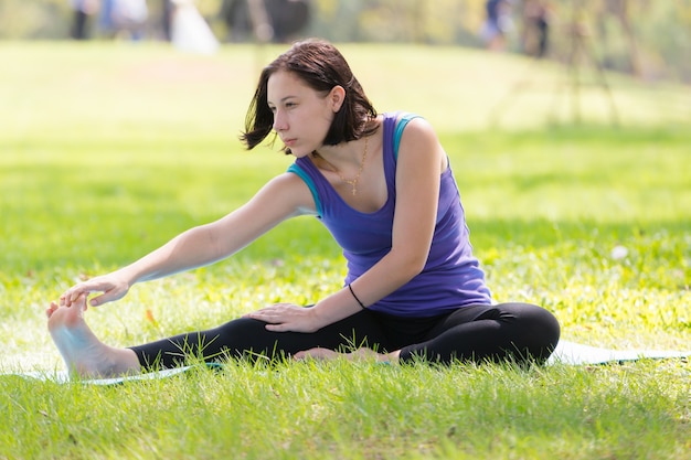 Holiday young woman doing yoga pose meditation in the public park Sport Healthy concept.