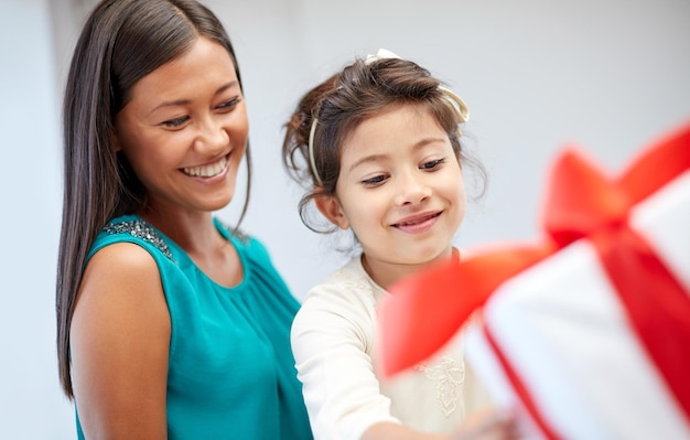 holidays, birthday family, childhood and people concept - happy mother and little girl with gift box at home