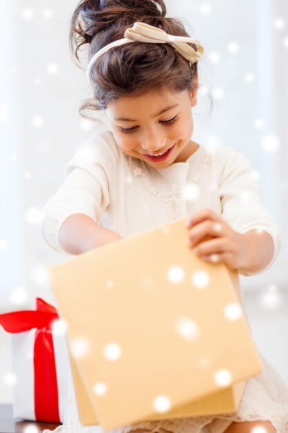 holidays, christmas, childhood and people concept - smiling little girl with gift box at home