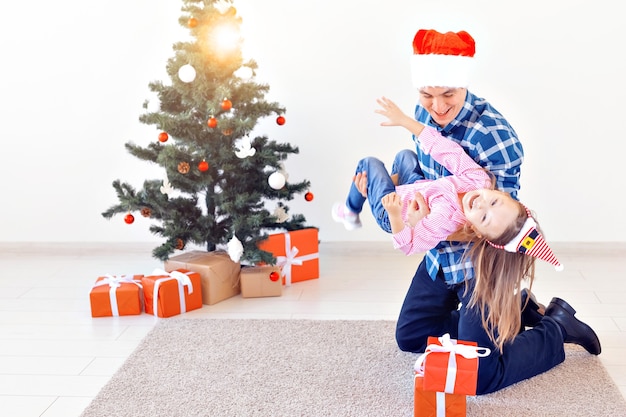 Holidays, christmas, family and happiness concept - funny father and daughter near christmas tree