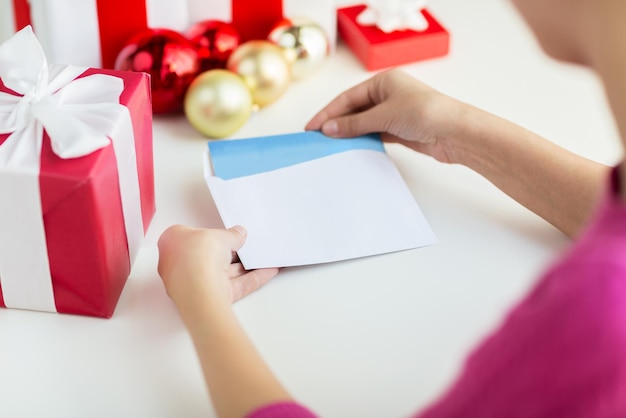 holidays, communication and people concept - close up of woman with letter and presents