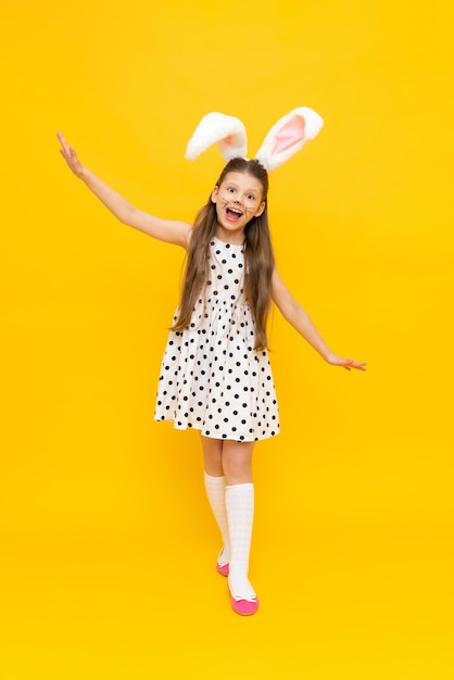 Holidays the concept of the Easter holiday Portrait of a beautiful girl a romantic little girl in a beautiful polka dot dress with bunny ears happily smiling celebrating Easter