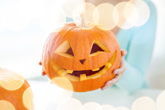 holidays, halloween, decoration and people concept - close up of woman with pumpkins at home