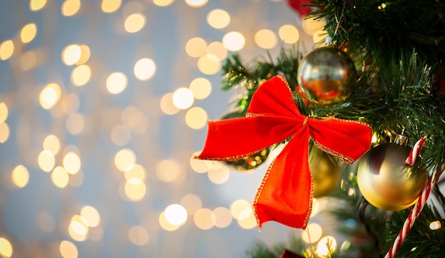 holidays, new year, decor and celebration concept - close up of christmas tree decorated with red bow and balls