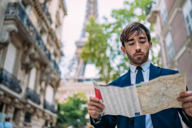 Holidays in Paris Man in a suit using a map in Paris France Street with Eiffel Tower view