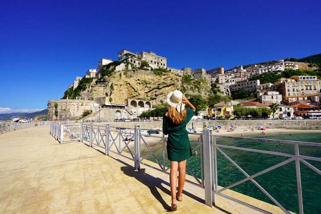 Holidays in Pizzo Calabro Italy Back view of beautiful fashion girl enjoying view of the fortress of Pizzo Calabria Summer vacation in Italy