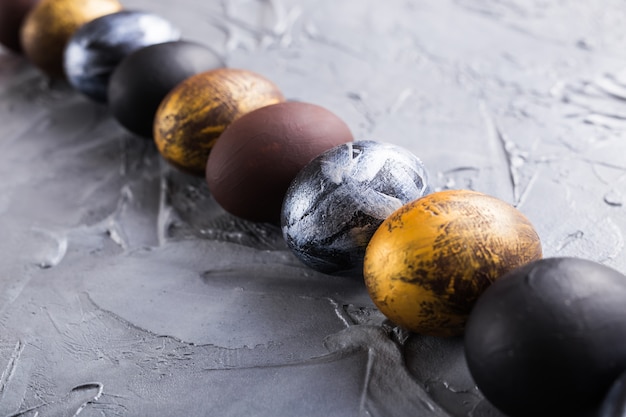 Holidays, traditions and Easter concept - Dark stylish easter eggs on grey background.