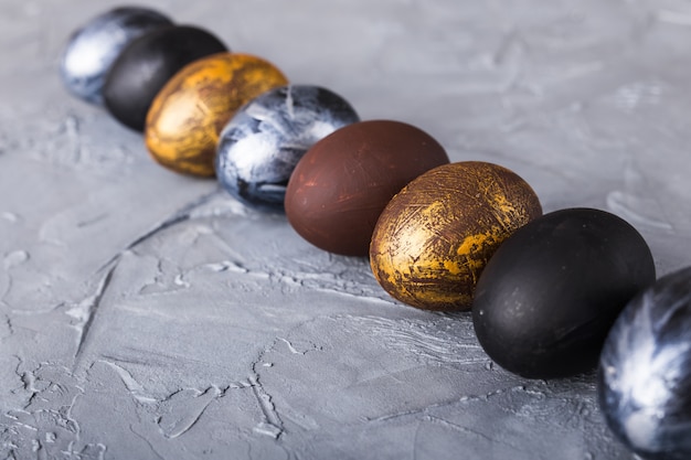 Holidays, traditions and Easter concept - Dark stylish easter eggs on grey background.