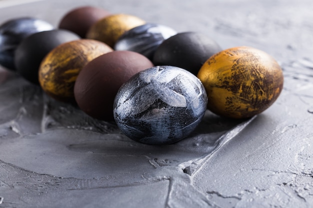 Holidays, traditions and Easter concept - Dark stylish easter eggs on grey background.