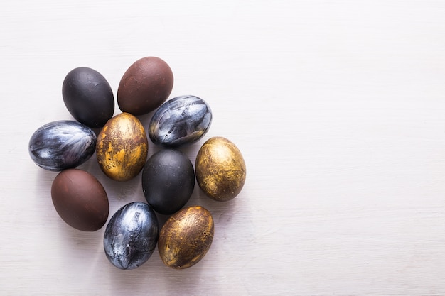 Holidays, traditions and Easter concept - Dark stylish easter eggs on white wooden background with copyspace.