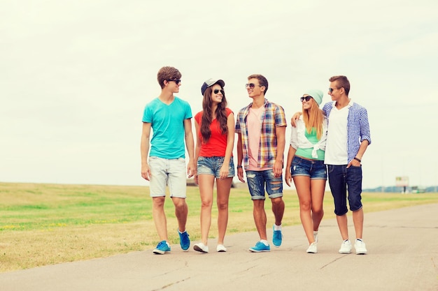 holidays, vacation, love and friendship concept - group of smiling teenagers walking outdoors