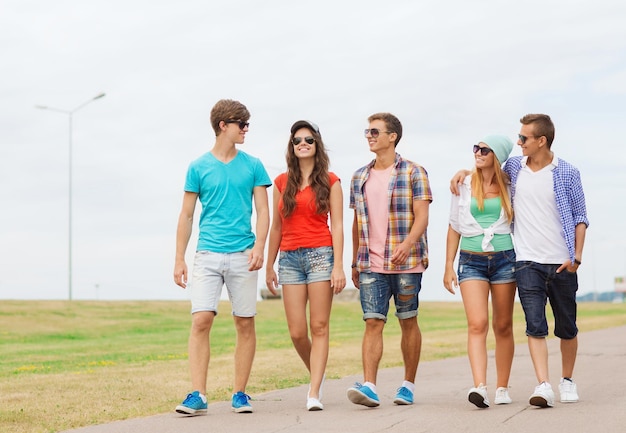 holidays, vacation, love and friendship concept - group of smiling teenagers walking outdoors