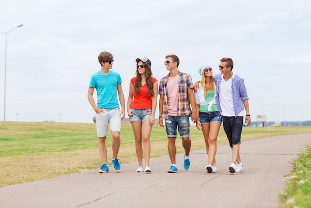 holidays, vacation, love and friendship concept - group of smiling teenagers walking outdoors