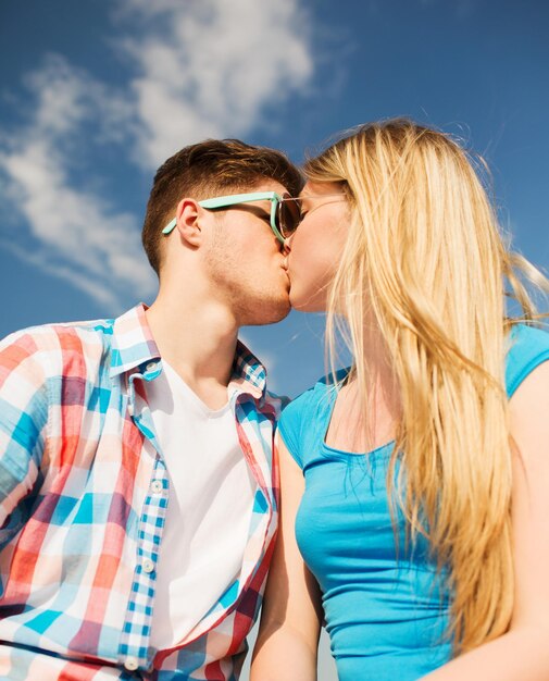 holidays, vacation, love and friendship concept - smiling couple kissing outdoors