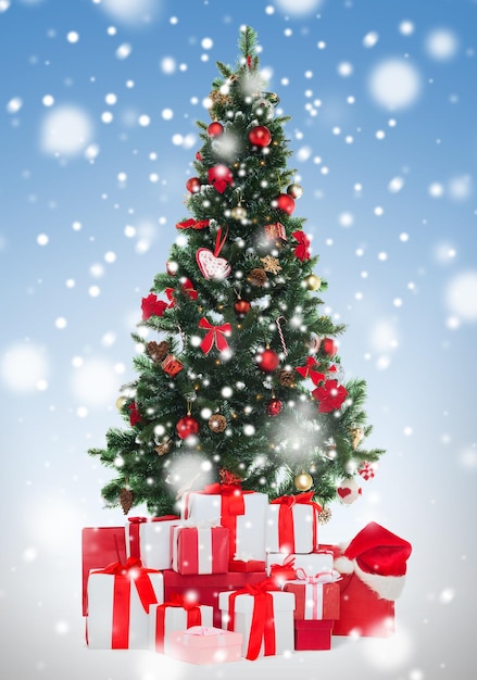 holidays, winter and celebration concept - f christmas tree and presents over blue background with snow