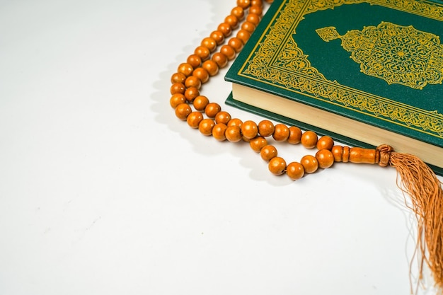 The Holy Al Quran with written arabic calligraphy rosary beads or tasbih on white background