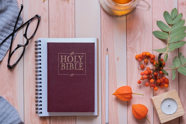 Holy bible and autumn cozy top view on wooden background Bible study autumn concept