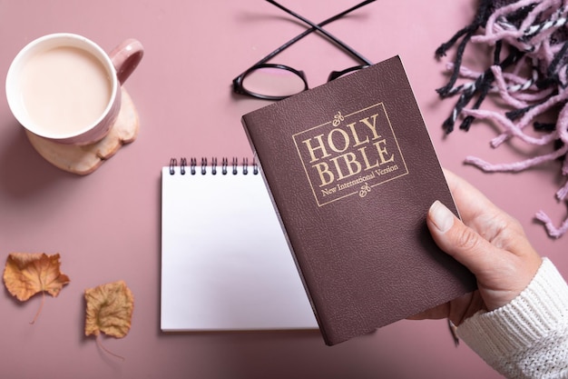 Holy Bible in female hand in sweater with a Cup of Coffee top view Holy Bible study concept