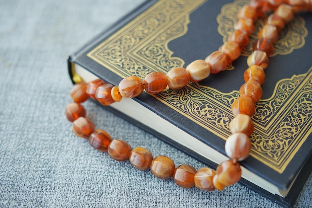 Holy book Quran and rosary on table close up