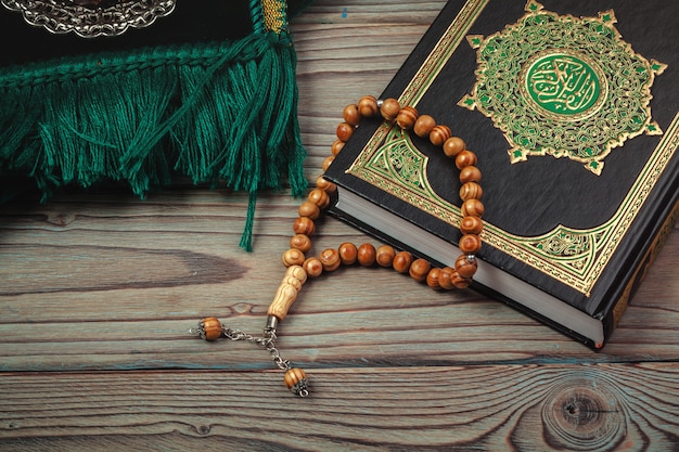 Holy Quran with beads over wooden surface