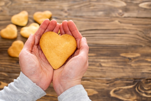 Home baking cookies hearts. A person is holding a cookie in the form of a heart.