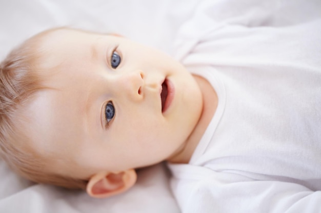 Home bed and face of baby relax resting and calm in nursery for sleeping or wake up in morning Family youth and closeup of infant newborn in bedroom for child development growth and wellness