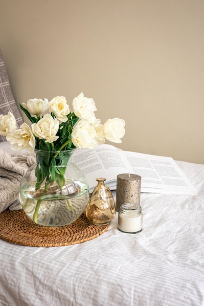 Home composition with a bouquet of tulips in a glass vase and candles