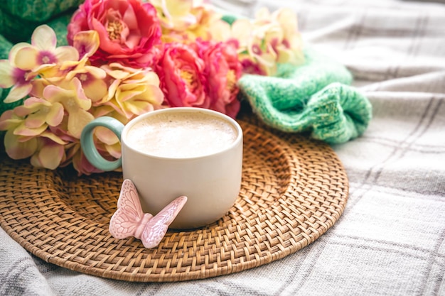 Home composition with a cup of coffee flowers and a knitted element