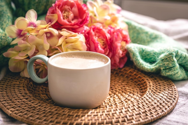 Home composition with a cup of coffee flowers and a knitted element