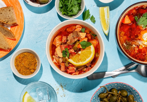 Home cooked solyanka meat soup served with lemon, olives and capers