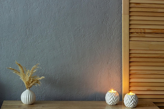 Home decor mockup empty gray painted concrete wall There is a vase with dry grass and lighted candles on the table Place for your text