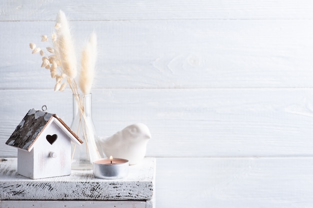 Home decor in Scandinavian style with pampas grass dry flowers on rustic background in monochrome style. Scented candles and birdhouse with copy space