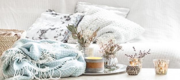 Home decorations in the interior. turquoise blanket and wicker basket with a vase of flowers and candles