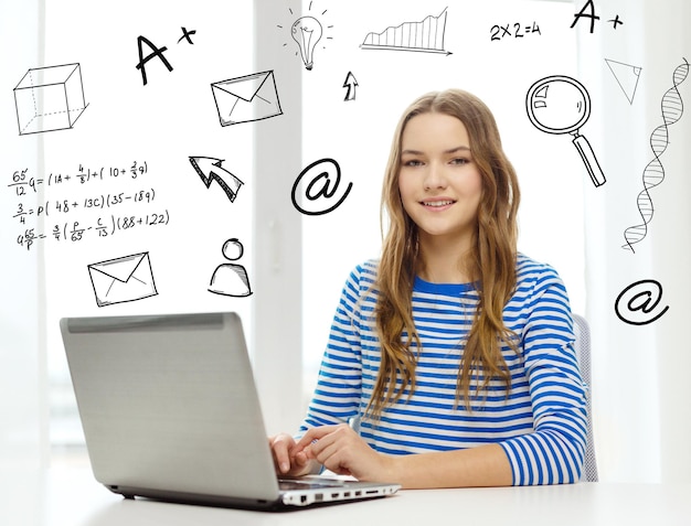 home, education, technology and internet concept - smiling teenage girl with laptop computer sitting at table at home