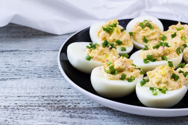 Home eggs stuffed with cheese and crab sticks topped with green onions