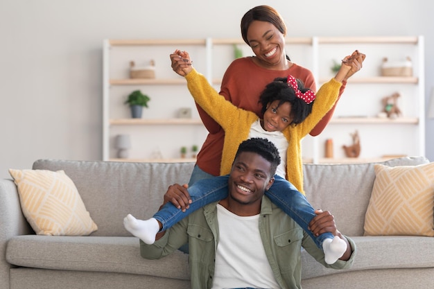 Home fun cheerful african american family of three fooling in living room