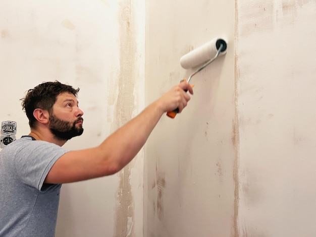 Photo home improvement caucaisan man applying wall treatment