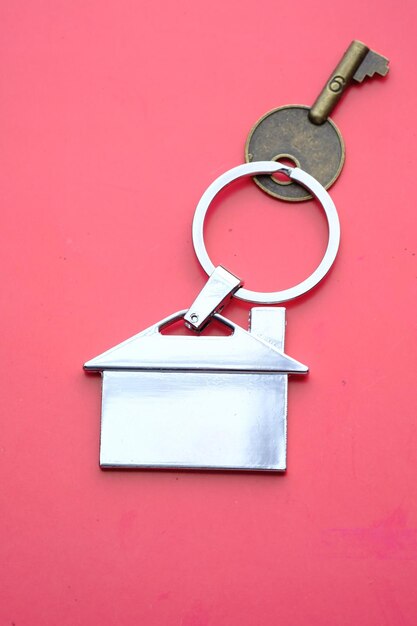 Photo a home key with an attractive houseshaped keychain set against a beautiful pink background