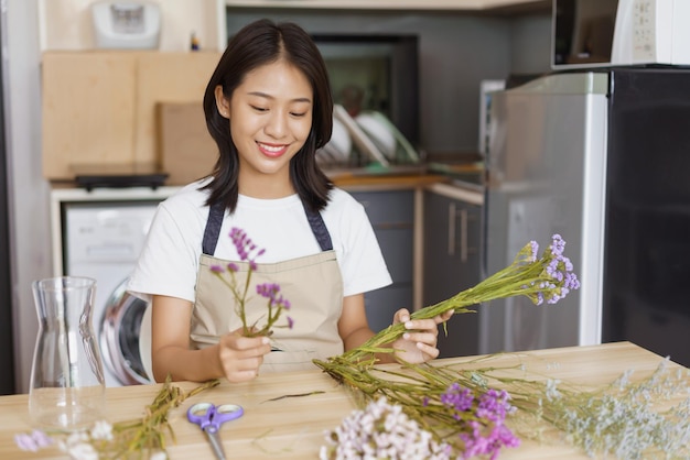 Home lifestyle concept Young woman sitting in kitchen room and arrange flowers in vase on table