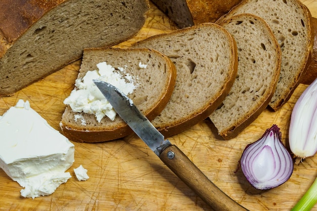 Home made bread on a wooden cutting board with curd cheese Decorated with fresh green onions or spring onions