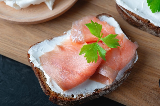 Home made bread on a wooden cutting board with curd cheese and pink salmon