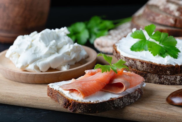 Home made bread on a wooden cutting board with curd cheese and pink salmon