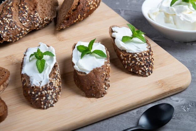 Home made bread on a wooden cutting board with curd cheese and ricotta and herbs Decorated with mint