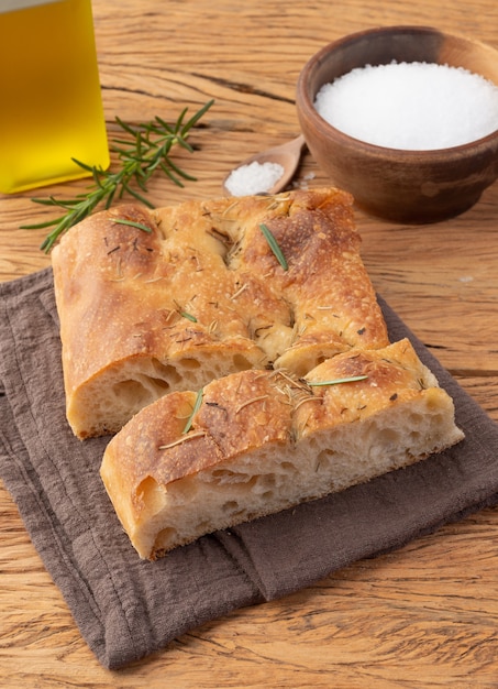 Home made focaccia with salt, olive oil and rosemary over wooden table.