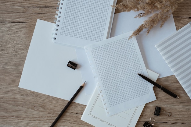 Home office desk workspace with blank paper sheets, notebook, pampas grass